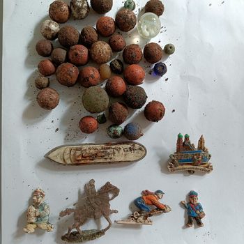 Fundstücke: Murmeln und Perlen, kleine Zinnsoldaten und ein Spielzeugschiff von der Margarinemarke Sanella